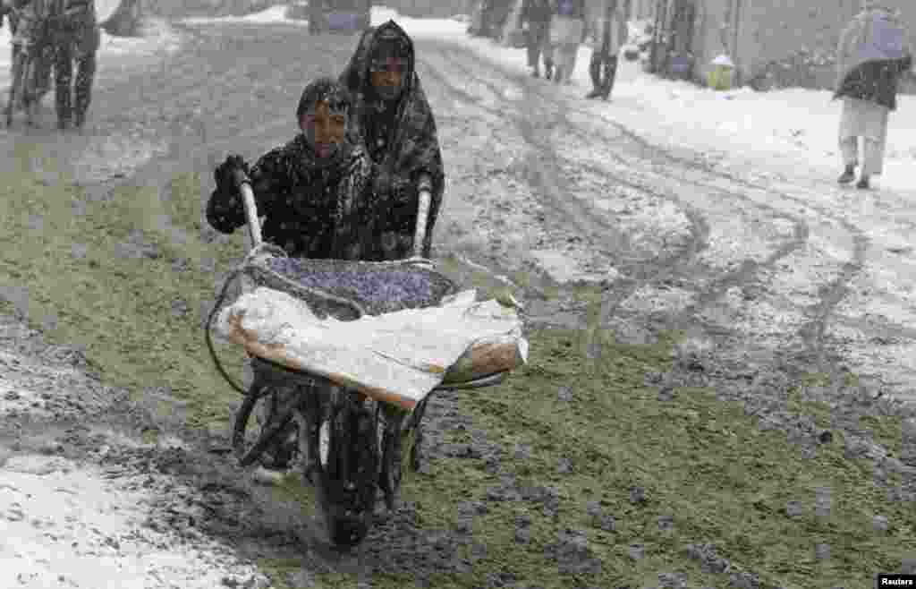 Afghan boys push their handcart along a street during the first snow in Ghazni Province. (Reuters/Mustafa Andaleb)