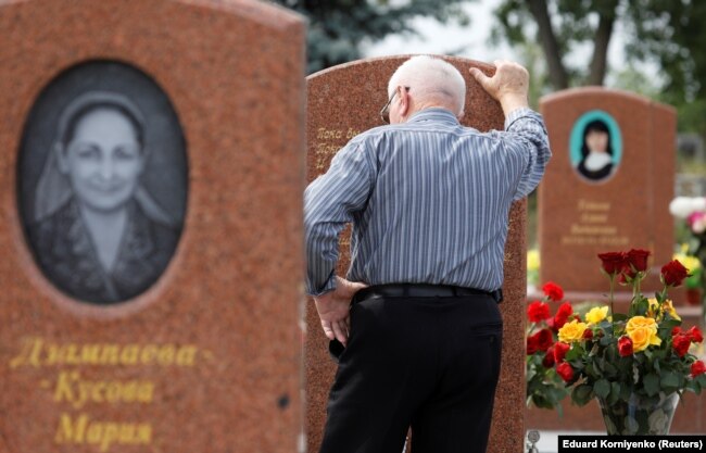 A man mourns at the cemetery where victims of the 2004 school siege are buried on the 15th anniversary of the siege in the southern Russian town of Beslan on September 2, 2019.