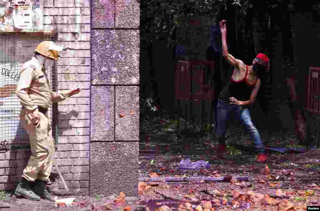 A Kashmiri student throws a projectile toward an Indian policemen during a protest in Srinagar on April 24. (Reuters/Danish Ismail)