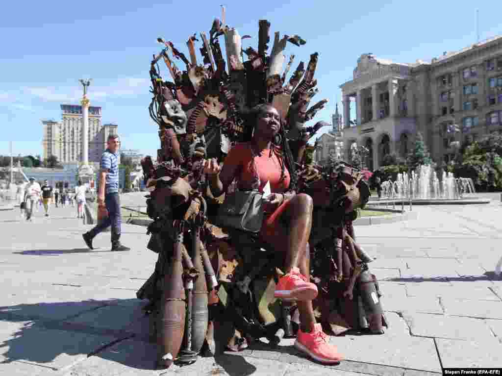 A woman in Kyiv poses for a photo on an &quot;Iron Throne&quot; inspired by the Game of Thrones TV series that was made by a Ukrainian volunteer using wreckage and debris from the eastern front. (epa-EFE/Stepan Franko)