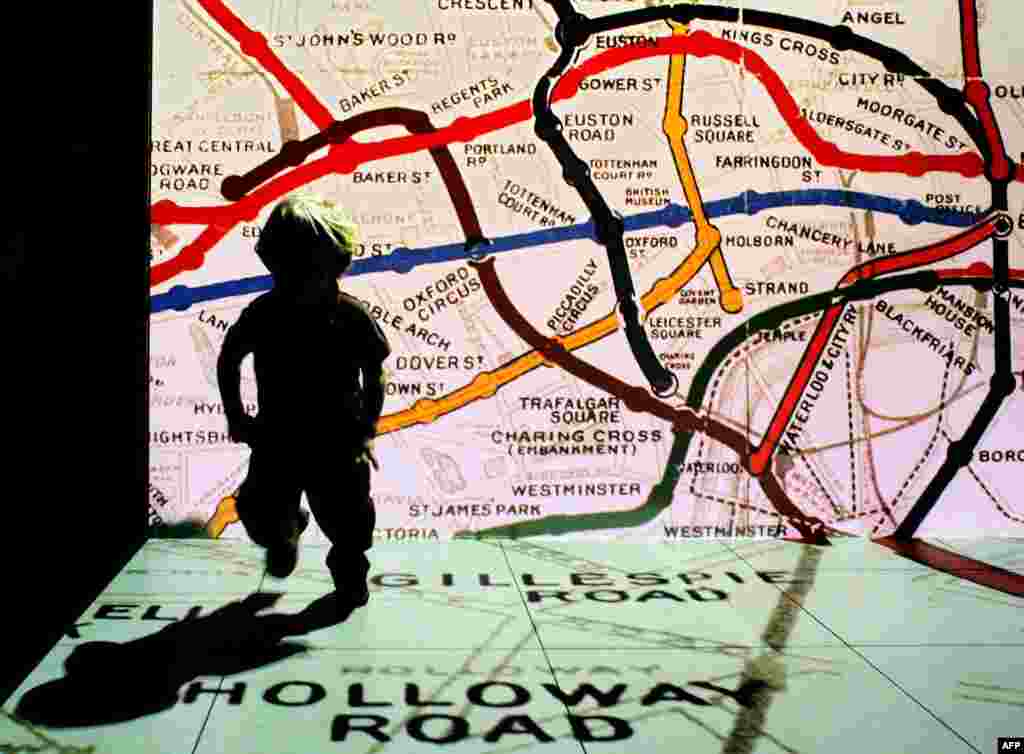 A young visitor to the London Transport Museum runs in front of an old Underground map.