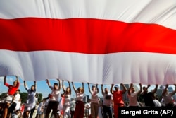 Opposition supporters wave a huge old Belarusian national flag as they rally in the center of Minsk on August 16, 2020.