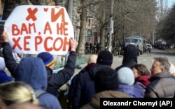 Люди стоять перед російськими військами на вулиці під час мітингу проти окупації в Херсоні, 14 березня 2022 року