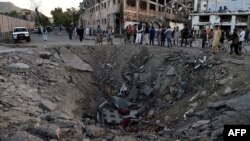 Afghan security forces and residents stand near the crater left by a deadly truck-bomb attack in Kabul on May 31.