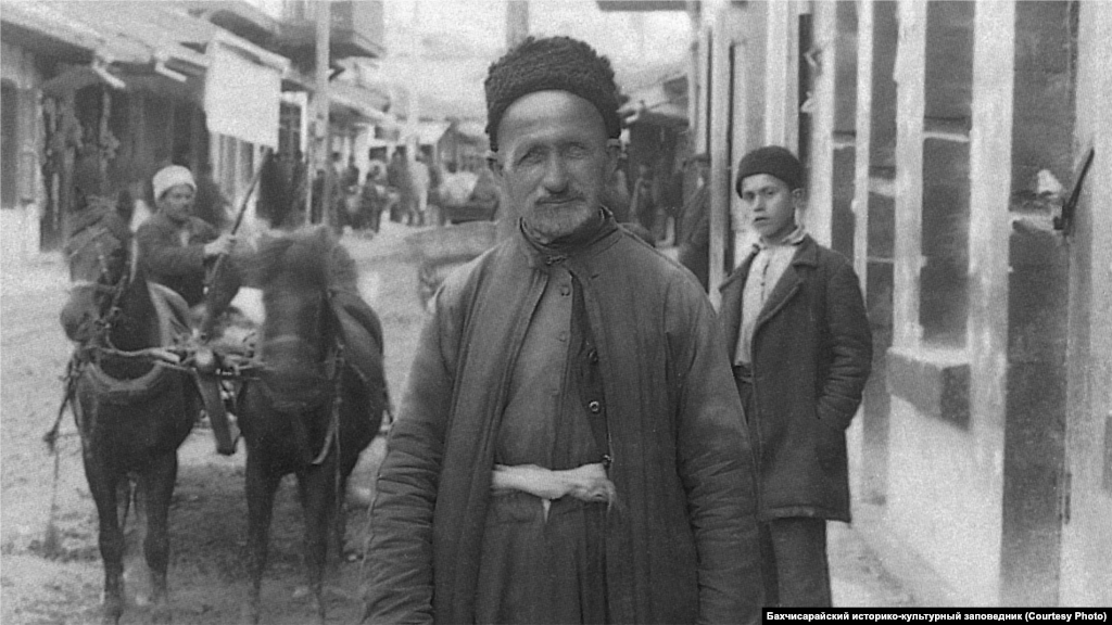 Bağçasaray sakini, 1920 seneleri.&nbsp; Erkekler başına qalpaq, taqiye ya da fes taqa edi. Keniş qollu kölmek keniş şalvarnen kiyilip quşaqlanğan edi. Kölmek üstüne dügmeli qısqa yelek, üstüne ise uzun qaftan kiye ediler