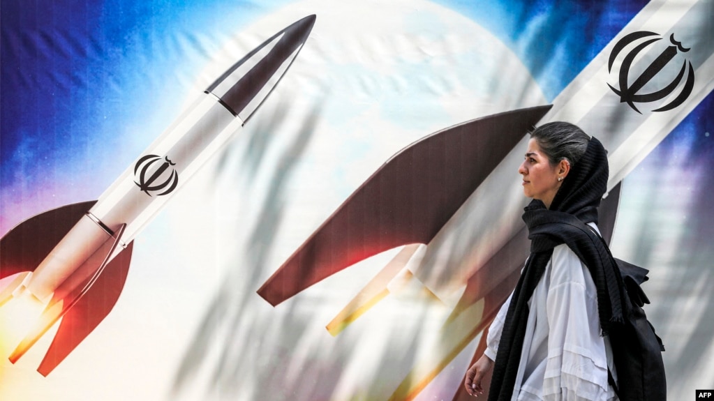 Жена преминава край плакат с ракети, носещи емблемата на Ислямска република Иран, Техеран, 15 април 2024 г.