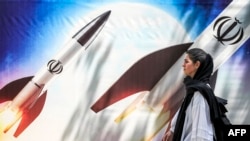 Një grua kalon pranë një pankarte me raketa në Teheran më 15 prill 2024. 