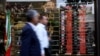 People walk past a currency exchange bureau in Tehran in May. 