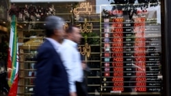 People walk past a currency exchange bureau in Tehran in May. 
