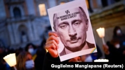 ITALY – A protester holds a picture of Russian President Vladimir Putin with a moustache and a symbol of swastika to resemble the Nazi dictator Adolf Hitler. Italy, February 25, 2022