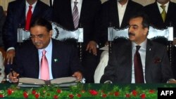 Pakistani President Asif Ali Zardari (left) signing a constitutional reform law as Prime Minister Yousuf Raza Gilani (R) looks on during a ceremony in Islamabad in April 2010.