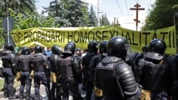 Polițiști în fața unui banner anti-LGBT la Chișinău, la 16 iunie 2024. 