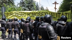 Polițiști în fața unui banner anti-LGBT la Chișinău, la 16 iunie 2024. 