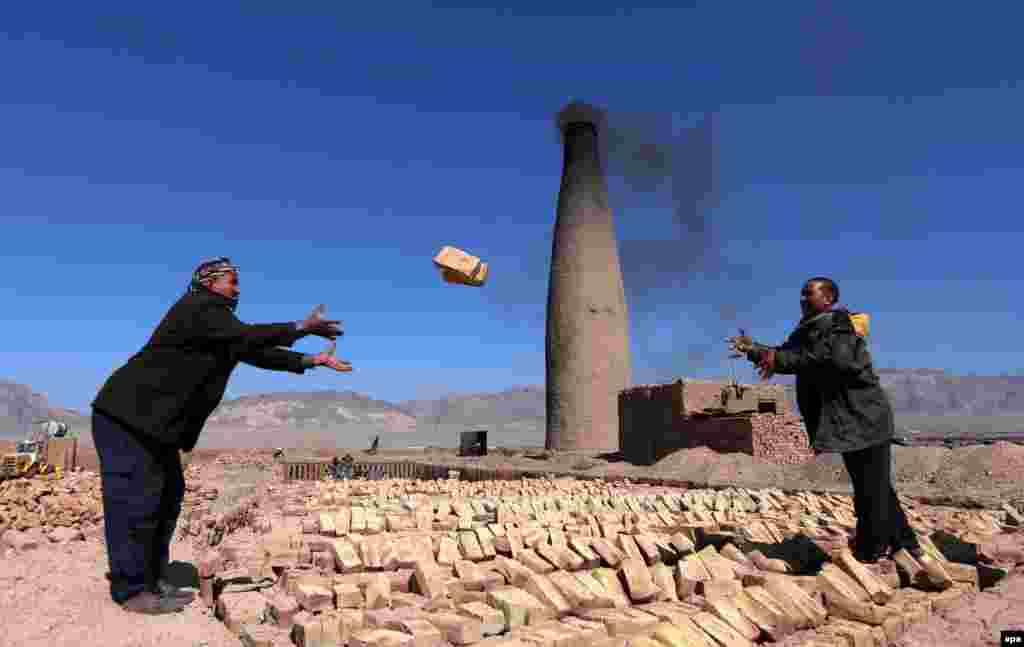 Afghan men at a brick kiln pile up new bricks in Herat. (epa/Jalil Rezayee)