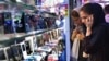 A woman talks on her mobile phone as she browses for mobile phones in Tehran. (file photo)