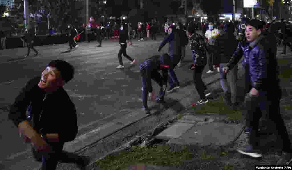 Protesters throwing stones at riot police in Bishkek.