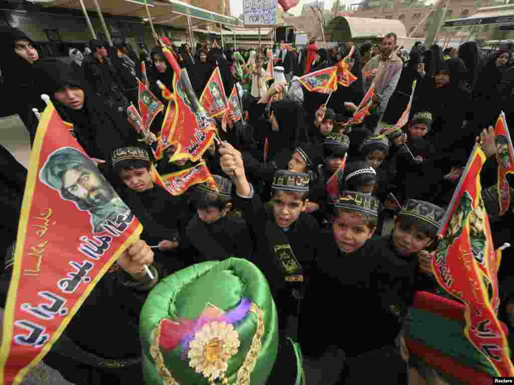 Children prepare for Ashura ceremony in Karbala, Iraq. They are wearing the traditional Muslim caps, taqiyah, inscribed for the occasion and waving banners that bear the likeness of Imam Hussein.