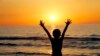 Iran -- An Iranian child raises his hands at sunset at a beach in the Caspian Sea port city of Mahmoud Abad, in northen Mazandaran province on June 16, 2016. / AFP PHOTO / ATTA KENARE