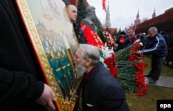 Поклонник Сталина целует икону с его изображением во время возложения цветов к могиле "вождя народов" у Кремлевской стены