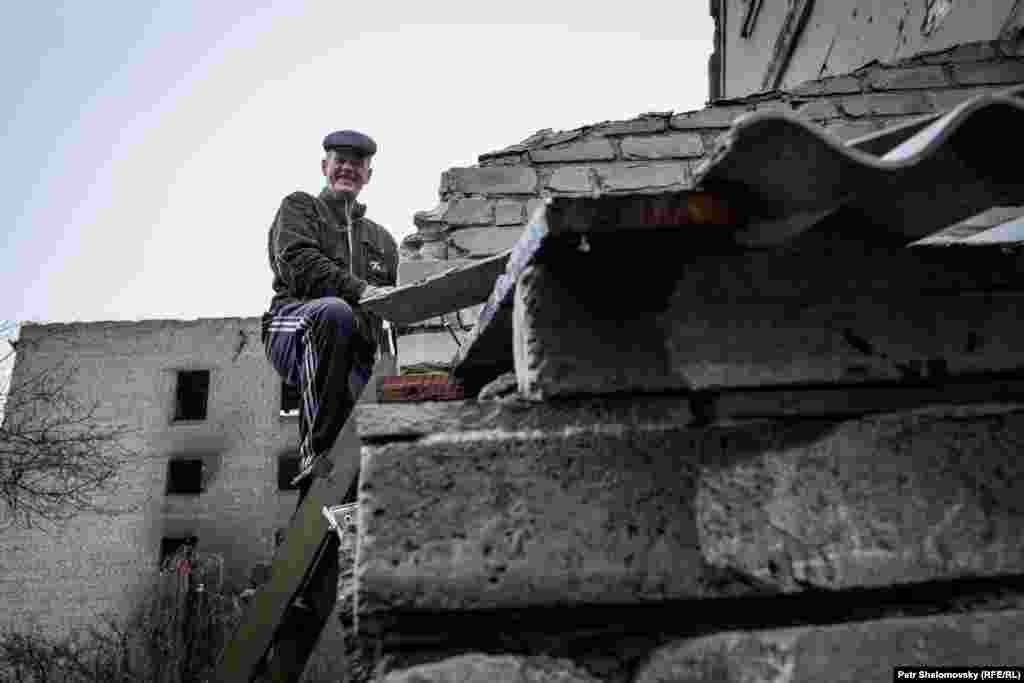 Чоловік лагодить дах свого пошкодженого будинку у Дебальцеві