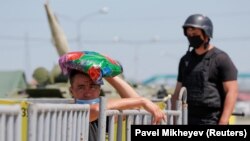 Сотрудник полиции и житель у ограждения, выставленного на съезде в закрытый на карантин город Алматы. 11 мая 2020 года.