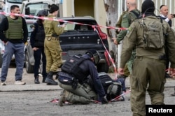 "Hizbullah" və İsrail arasında gərginliyin artması fonunda polis avtobusun zədələndiyi ərazidə yoldakı dəliyə baxış keçirir.