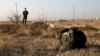 IRAN -- A police officer stands guard as debris is seen from an Ukrainian plane which crashed in Shahedshahr, southwest of the capital Tehran, Iran, Wednesday, Jan. 8, 2020. 