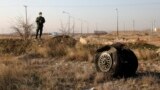 IRAN -- A police officer stands guard as debris is seen from an Ukrainian plane which crashed in Shahedshahr, southwest of the capital Tehran, Iran, Wednesday, Jan. 8, 2020. 