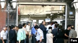 People stand in front of a currency exchange office in Tehran.