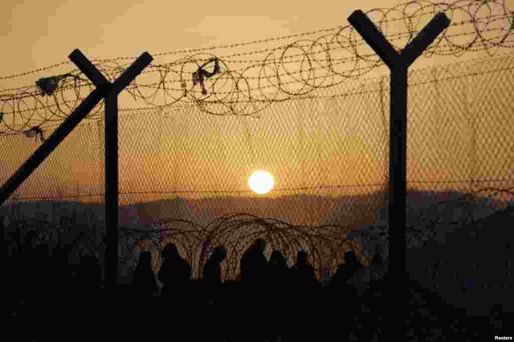 Migrants stand behind a border fence at the Greek-Macedonian border after additional passage restrictions imposed by Macedonian authorities left hundreds of them stranded near the village of Idomeni on February 23. (Reuters/Marko Djurica)