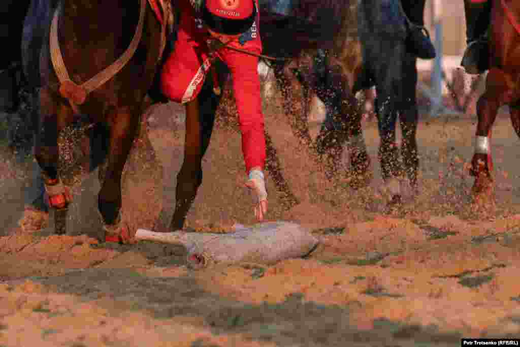 A player reaches down to grab a synthetic goat carcass during a kok-boru match at the World Nomad Games in Kazakhstan.&nbsp;