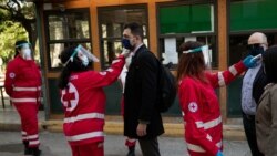 Volonteri Crvenog krsta mere temperaturu ljudima koji žele da uđu u zgradu suda, Atena, 30. april