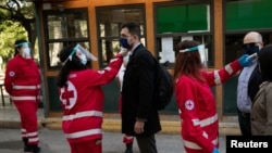 Волонтери на Црвен крст мерат температура на луѓе пред за влезат во Суд во Грција. 