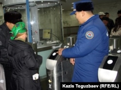 Жолаушылар метро турникеті арқылы өтіп жатыр. Алматы, 12 желтоқсан 2011 жыл.
