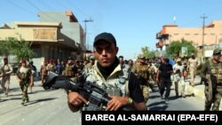 File - Members of Iraqi Shiite group known as Hashd al-Shaabi (The Popular Crowd) patrol an area in Tuz, southern Kirkuk city, Iraq, 17 October 2017.