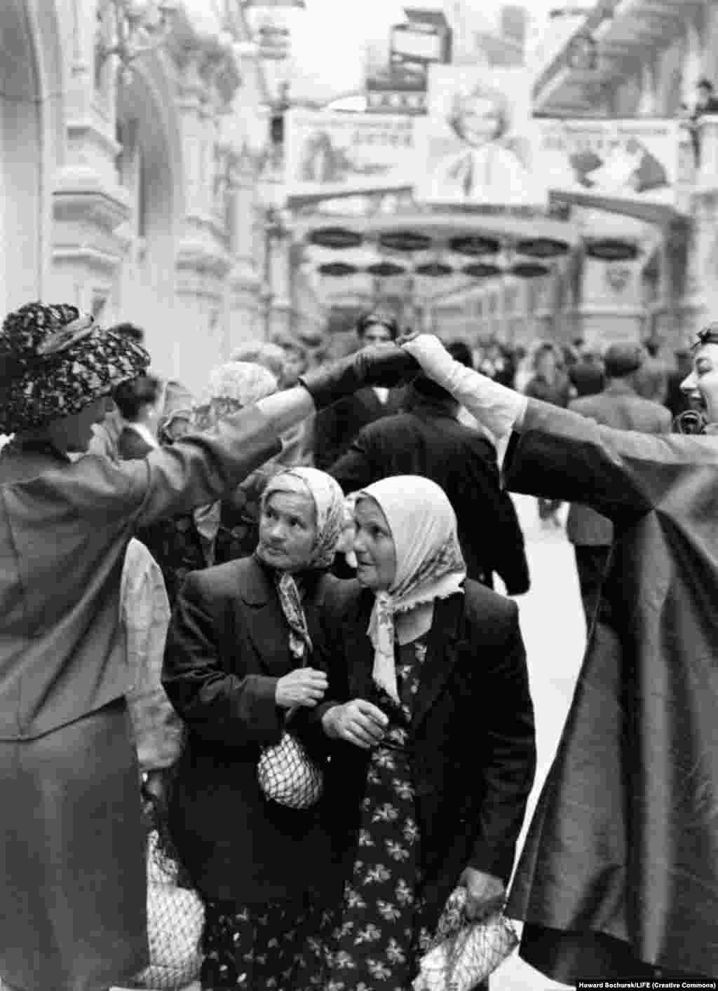 Two local women are caught up in the spectacle as models stroll through the GUM department store, across the square from the Kremlin.