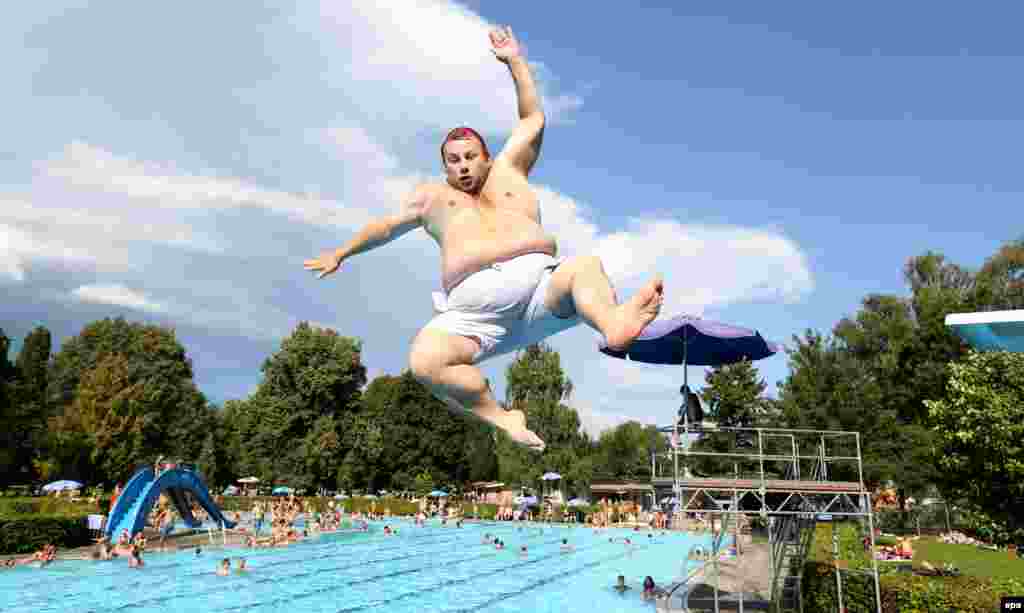 A man jumps into the water from a springboard at a public swimming pool in Mengen, Germany. (epa/Thomas Warnack)