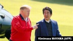 Japan's Prime Minister Shinzo Abe (R) listens to US President Donald Trump as they walk before playing a round of golf at Mobara Country Club in Chiba on May 26, 2019.