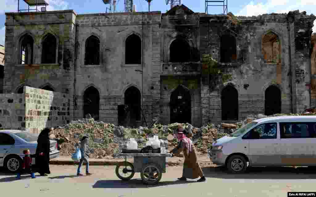 A street peddler pushes a cart carrying plastic containers down a bombed-out street in the Syrian city of Azaz, near the Turkish border. (AFP/Zein al-Rifa)