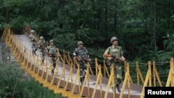 Indian Border Security Force soldiers patrol over a footbridge built over a stream near the Line of Control (file photo).