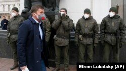 Як узви порлумони Украина аз назди муҳофизони ниқобпӯш гузашта, ба ҷойи кор меравад. 17-уми марти 2020