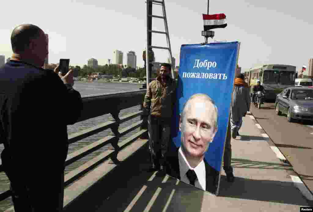 A worker poses for a picture with a banner of Vladimir Putin before hanging it along a bridge in central Cairo ahead of the Russian president&#39;s visit on February 9. (Reuters/Asmaa Waguih)
