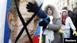 Demonstrators at an anti-Putin event earlier this month hold a defaced portrait of Prime Minister Vladimir Putin.