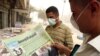 Iraqi men wearing surgical masks against a vicious sandstorm read an Iraqi paper with news of U.S. Vice President Joe Biden's visit on July 5.