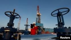 A worker checks a valve on an oil pipe at the LUKoil-owned Imilorskoye oil field outside the western Siberian city of Kogalym.