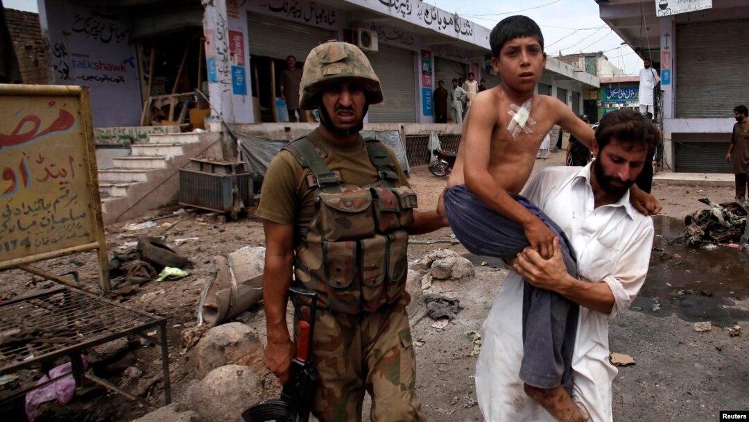 A security official carries a boy injured in the Peshawar attack on June 30.