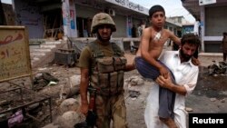 A security official carries a boy injured in the Peshawar attack on June 30.