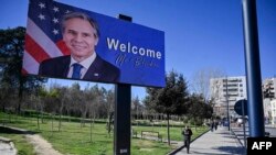 A man walks past a billboard depicting U.S. Secretary of State Antony Blinken displayed in Tirana on February 15.