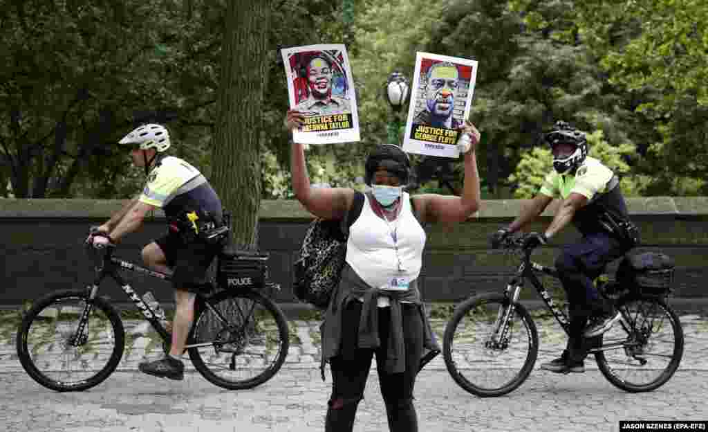A protestor holds up two signs one for Breonna Taylor (Left) and the other for George Floyd while demonstrating past two members of the New York City Police Department down 5th Avenue's museum mile in New York, USA, 11 June 2020, over the death of George Floyd.