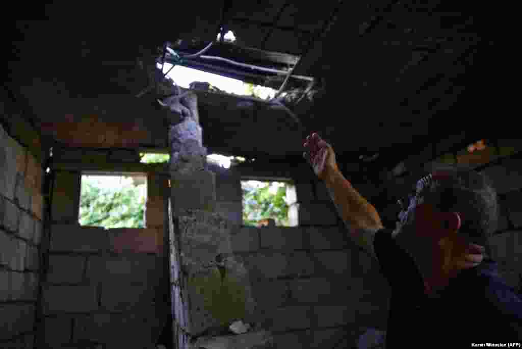 A man in the Armenian village of Aygepar points to his roof, which was damaged by shelling.